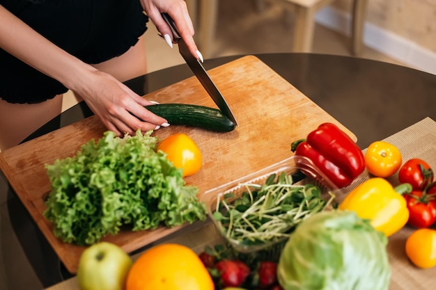 Frau steht in der Küche und kocht Salat mit gesundem Essen