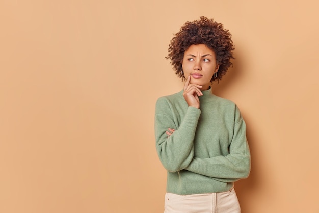 Frau steht in nachdenklicher Pose konzentriert weg grübelt über etwas Wichtiges Posen gegen Beige mit Leerzeichen für Ihre Werbeinhalte oder Promotion