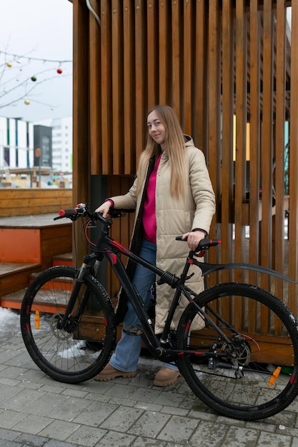 Frau steht neben dem Fahrrad auf dem Bürgersteig