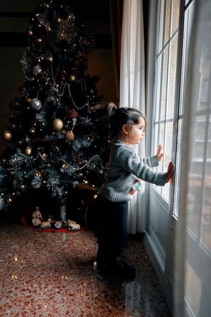 Foto frau steht neben dem weihnachtsbaum