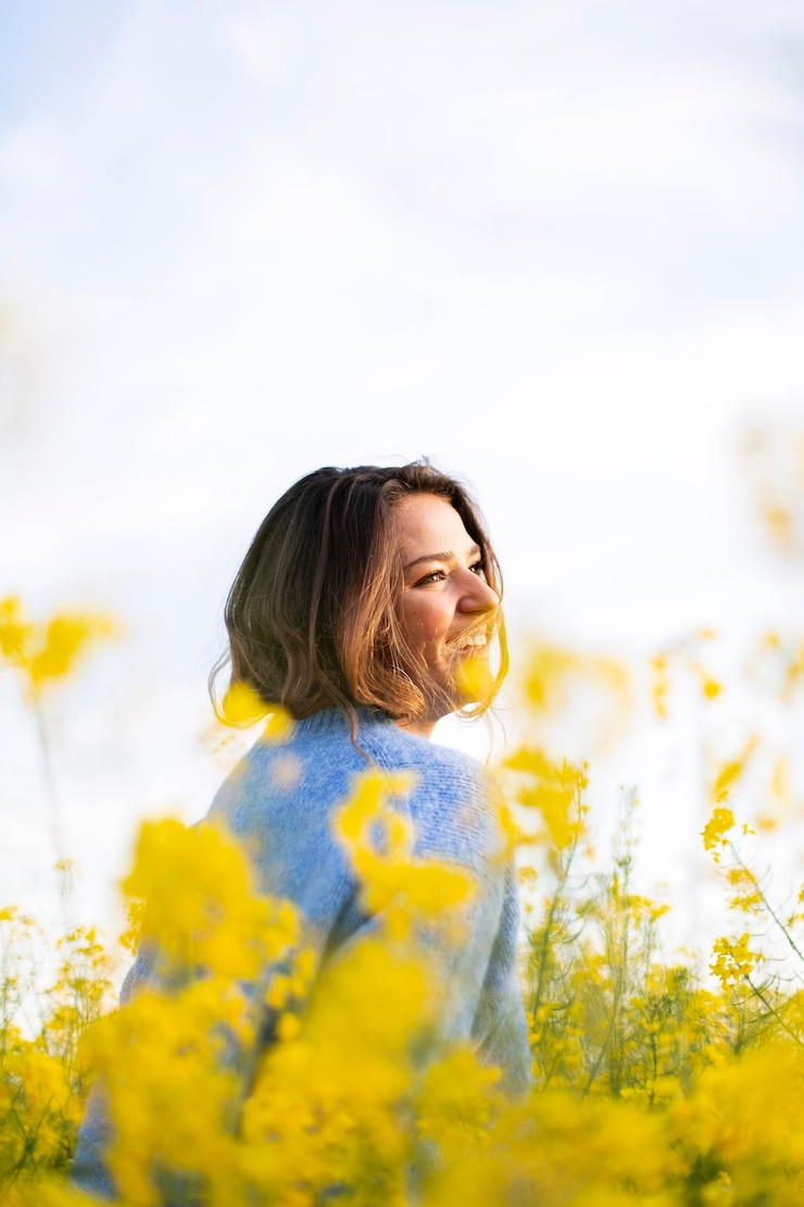 Foto frau steht neben gelben blumen auf dem feld