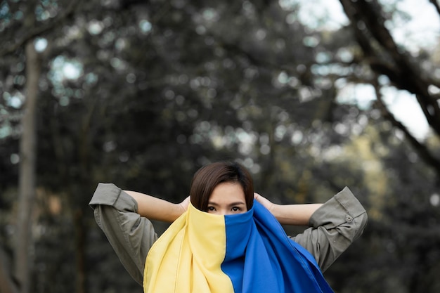 Foto frau steht und hält ukraine-flagge speichern sie die ukraine, stoppen sie den krieg