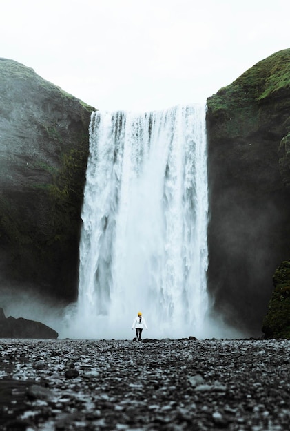 Frau steht vor Wasserfall Skógafoss, Island