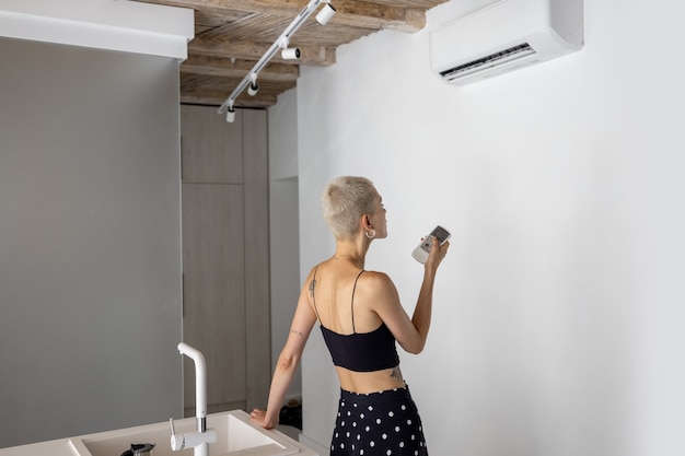 Frau stellt die Temperatur an der Klimaanlage zu Hause ein