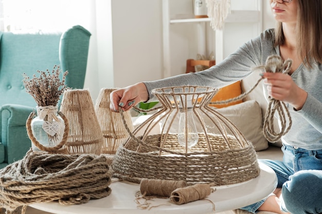 Frau stellt zu Hause handgefertigte DIY-Lampe aus Juteseil her