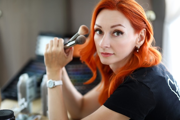 Frau Stylistin hält professionelle Make-up Pinsel Schönheitssalon Meister sitzt am Arbeitsplatz mit