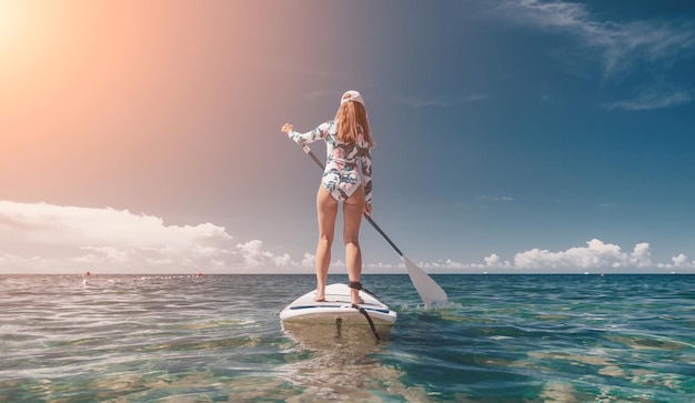 Frau sup Meer glücklich gesund fitte Frau im Bikini entspannt sich auf einem sup Surfbrett, das auf dem klaren schwimmt