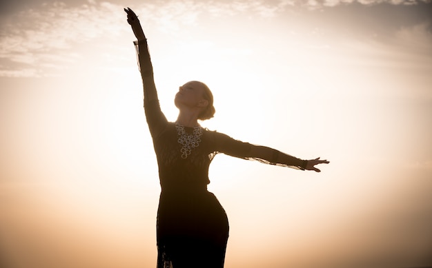 Frau tanzt bei Sonnenaufgang