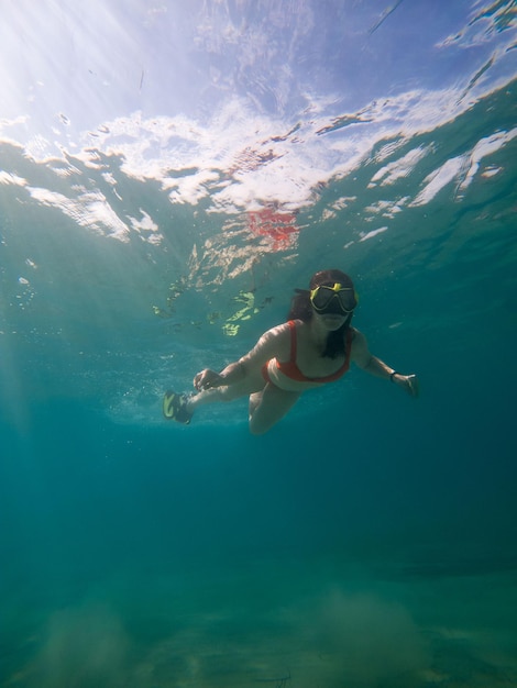 Frau taucht unter Wasser in Tauchermaske und Flossen