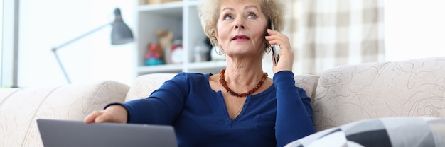 Frau telefoniert mit Laptop auf dem Schoß