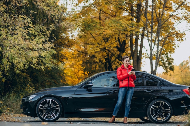 Frau telefoniert und steht an ihrem Auto