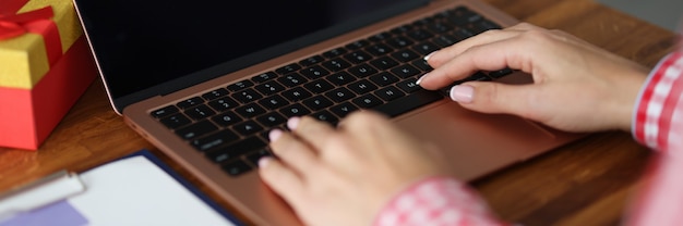 Frau tippt auf Laptop-Tastatur am Tisch Nahaufnahme