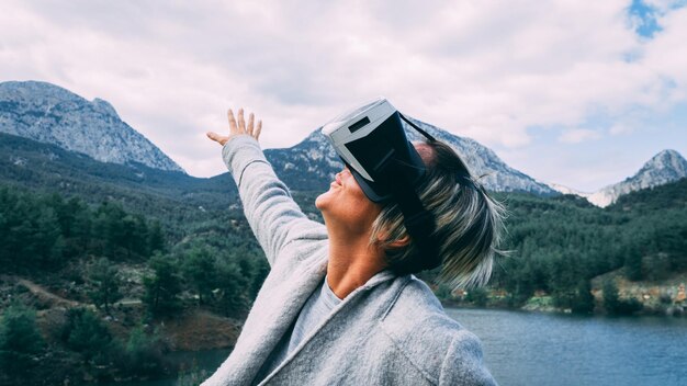 Foto frau trägt einen virtual-reality-simulator gegen berge und himmel