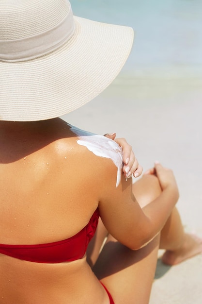 Frau trägt Sonnencreme auf die gebräunte Schulter auf Schönheitshautpflege alternde Körperpflege