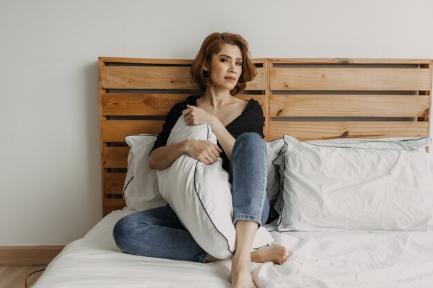 Frau trägt volles Make-up entspannt sich auf dem Bettkonzept der Einsamkeit