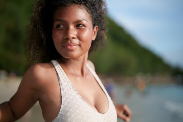 Frau trainiert und dehnt Muskeln vor dem Training im Freien Portrait sexy asiatische afrikanische Dame bereitet sich auf Fitness am Strand vor