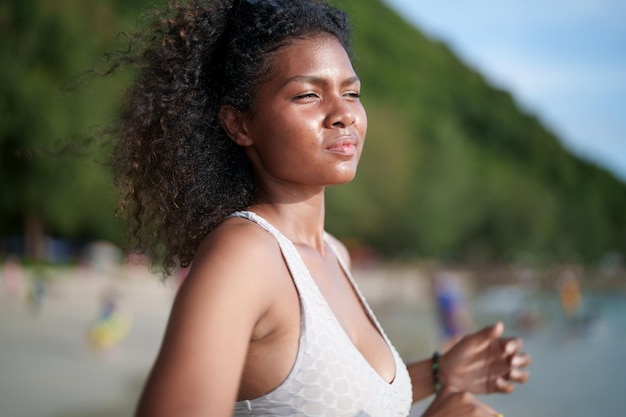 Frau trainiert und dehnt Muskeln vor dem Training im Freien Portrait sexy asiatische afrikanische Dame bereitet sich auf Fitness am Strand vor