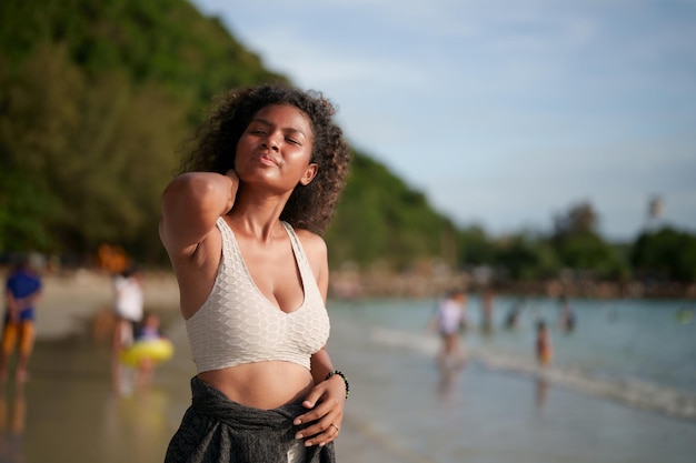 Frau trainiert und dehnt Muskeln vor dem Training im Freien Portrait sexy asiatische afrikanische Dame bereitet sich auf Fitness am Strand vor