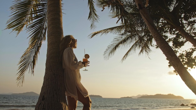 Frau trinkt Ananas-Cocktail Pina Colada in der Nähe von Palmen in weißen Hemd-Sonnenbrillen Konzept Rest tropisches Meer Reisen Tourismus Sommerferien