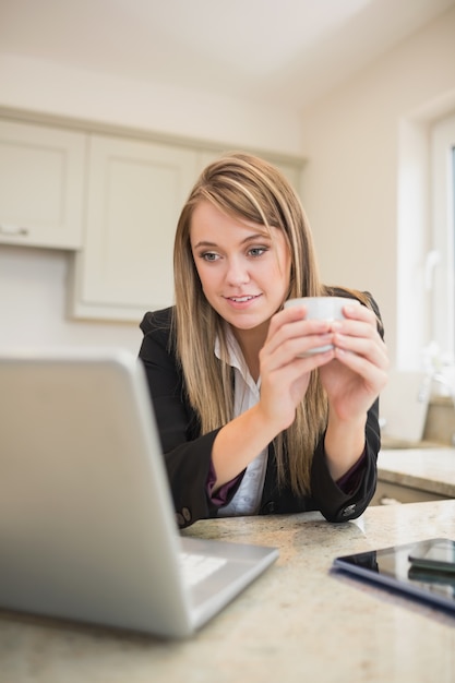 Frau trinkt einen Kaffee beim Arbeiten mit Multimedia