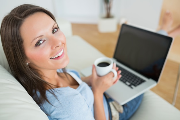 Frau trinkt einen Kaffee und mit ihrem Laptop