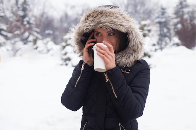 Frau trinkt ihr heißes Getränk aus der Tasse Wintersaison