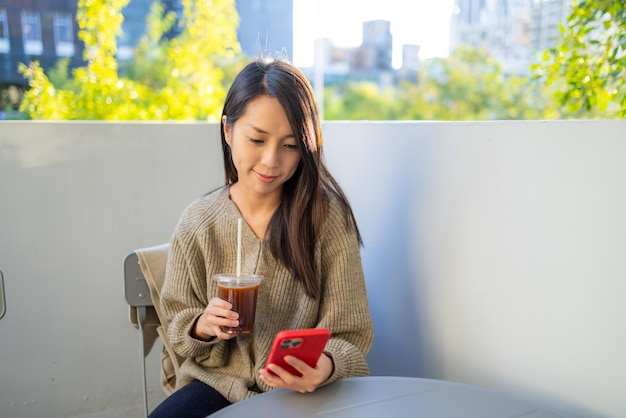 Frau trinkt Kaffee im Café und benutzt ihr Handy