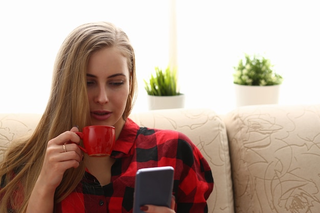 Frau trinkt Kaffee und schaut auf Laptop