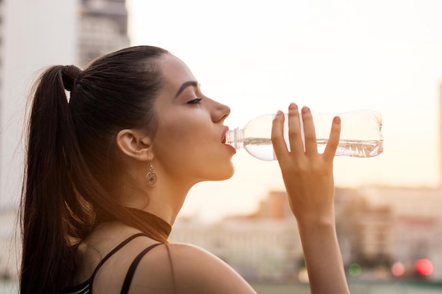 Frau trinkt Wasser aus der Flasche Seitenansicht des weiblichen Gesichts wenig Energie