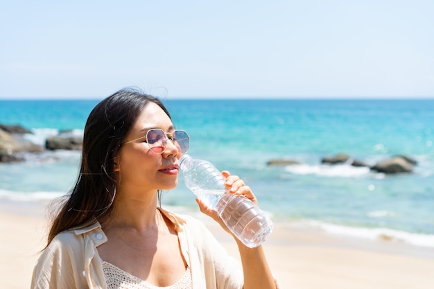 Frau trinkt Wasser aus Plastikflasche im Sommersonnenlicht am Meer Konzept der Gesundheit und Frische Durstwasserreinigung Closeup Copy Space