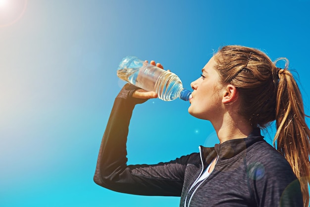 Frau trinkt Wasser, Gesundheit und Fitness mit blauem Himmel, Sportlerin im Freien mit Flüssigkeitszufuhr und Mockup-Platz, Sportübung und weibliche Person mit H2O-Getränk in der Flasche, Training und Trainingspause