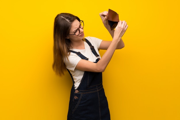 Frau über der gelben Wand, die eine Geldbörse hält