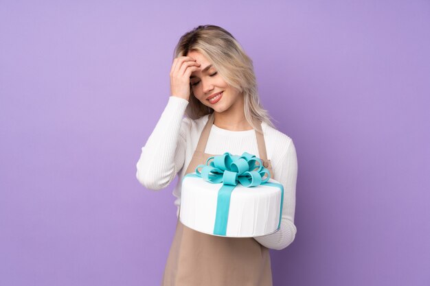 Frau über lokalisiertem Hintergrund, der einen großen Kuchen hält