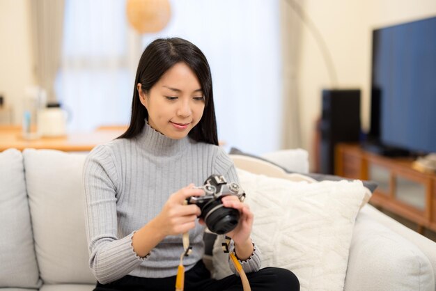 Frau überprüft das Foto auf der Digitalkamera zu Hause