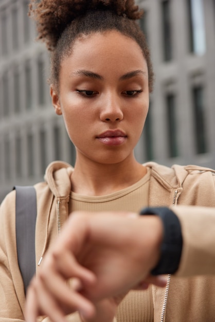 Frau überprüft die Zeit auf Smartwatch überwacht Fitnessergebnisse in Sportkleidung verbrennt viele Kalorien nach hartem Training im Freien