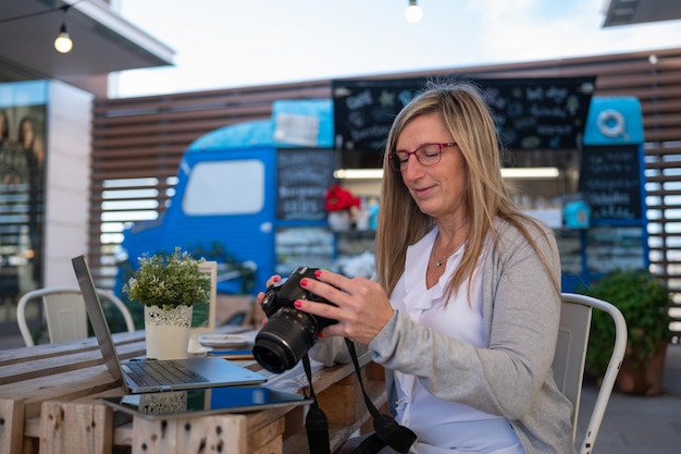 Frau überprüft Fotos auf einer Spiegelreflexkamera in einem Café