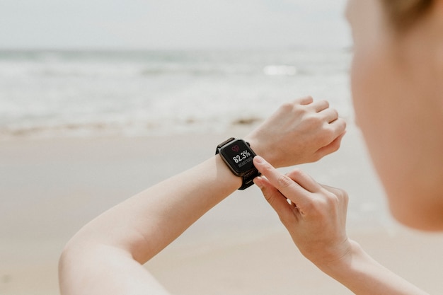 Foto frau überprüft ihre smartwatch am strand