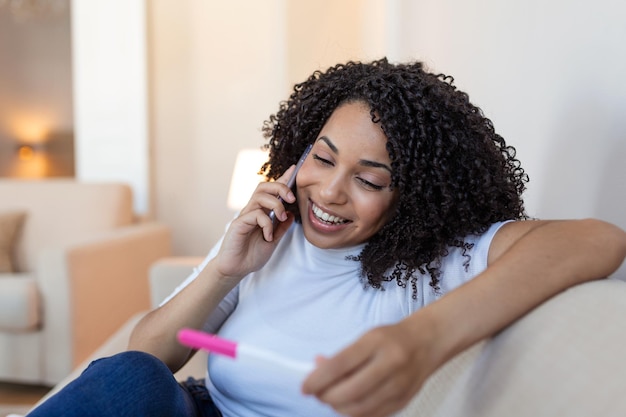 Frau überprüft morgens freudig ihren Schwangerschaftstest Sie benutzt das Handy für gute Nachrichten