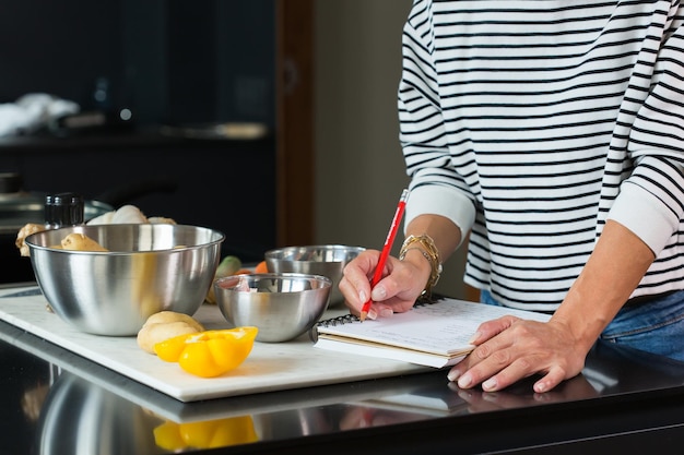 Frau überprüft Rezept beim Kochen von Apfelkuchen