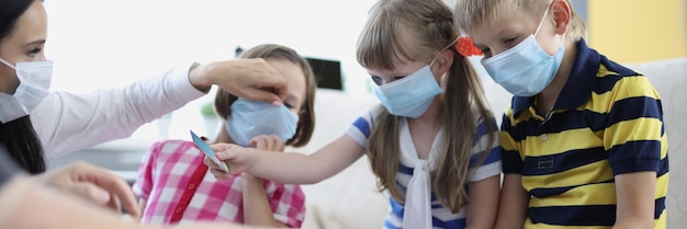 Frau überprüft ständig die Gesundheit von Kindern und bittet darum, eine Gesichtsmaske zu tragen, um die Ausbreitung von Covid zu verhindern