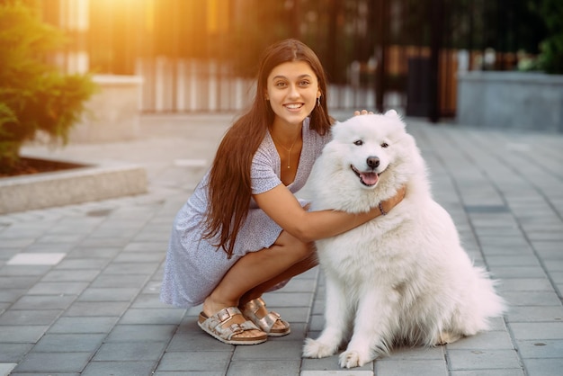 Frau umarmt einen großen Hund bei Sonnenuntergang