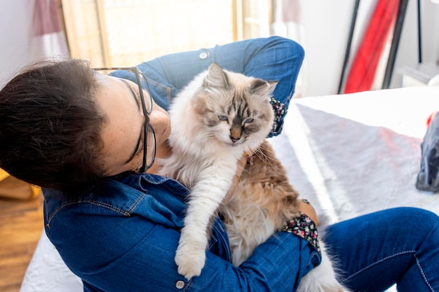 Frau umarmt ihre Katze, weil er sie nicht zu Hause arbeiten lässt