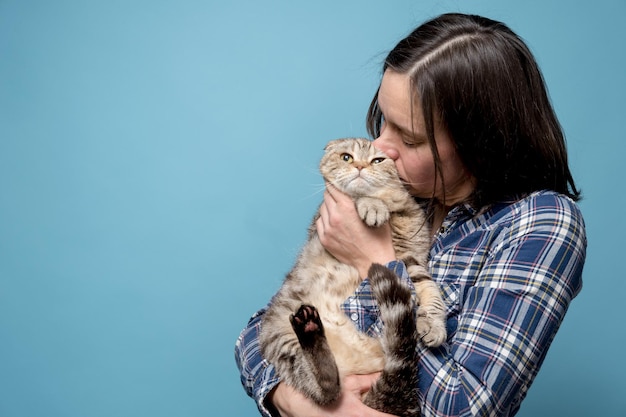 Frau umarmt und küsst ihre entzückende Katze Scottish Fold. Konzept der Liebe und des Respekts für Tiere