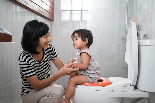 Frau und Baby kacken mit Toilettenhintergrund im Badezimmer