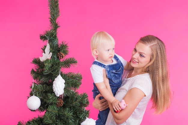 Frau und ihr Kind posieren neben dem Weihnachtsbaum