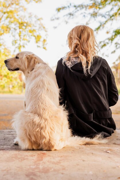 Frau und ihr Retrieverhund sitzen zusammen auf der Straße