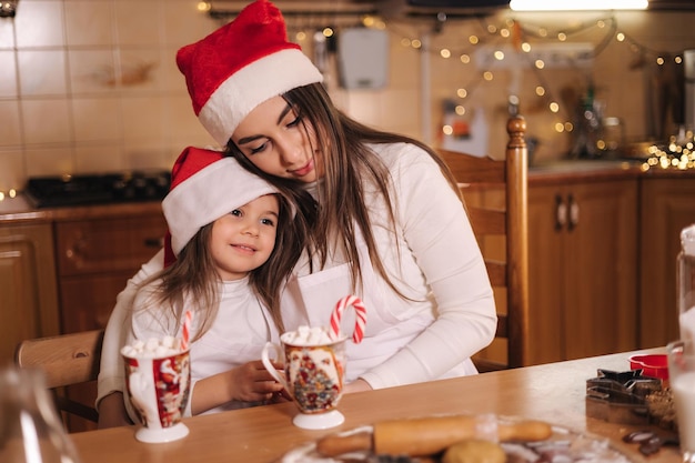 Frau und ihre kleine Tochter trinken leckeren Kakao mit Marshmallow im Küchenhaus dekoriert auf