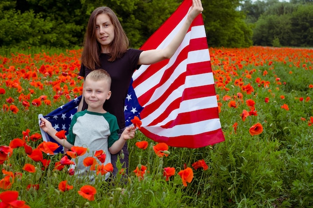 Frau und Junge stehen in amerikanische Flagge gehüllt mitten in einem Feld roter Blumen