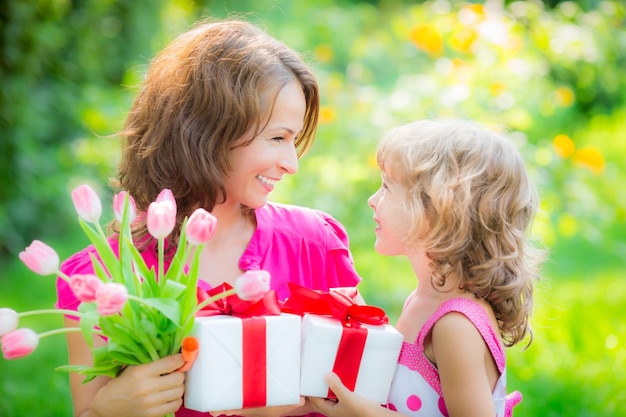 Frau und Kind mit Blumenstrauß vor grünem, unscharfem Hintergrund Frühlingsfamilienurlaub Konzept Frauentag