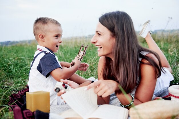 Frau und Kind mit Flugzeug in den Händen haben gute Zeit beim Picknick auf dem Feld.